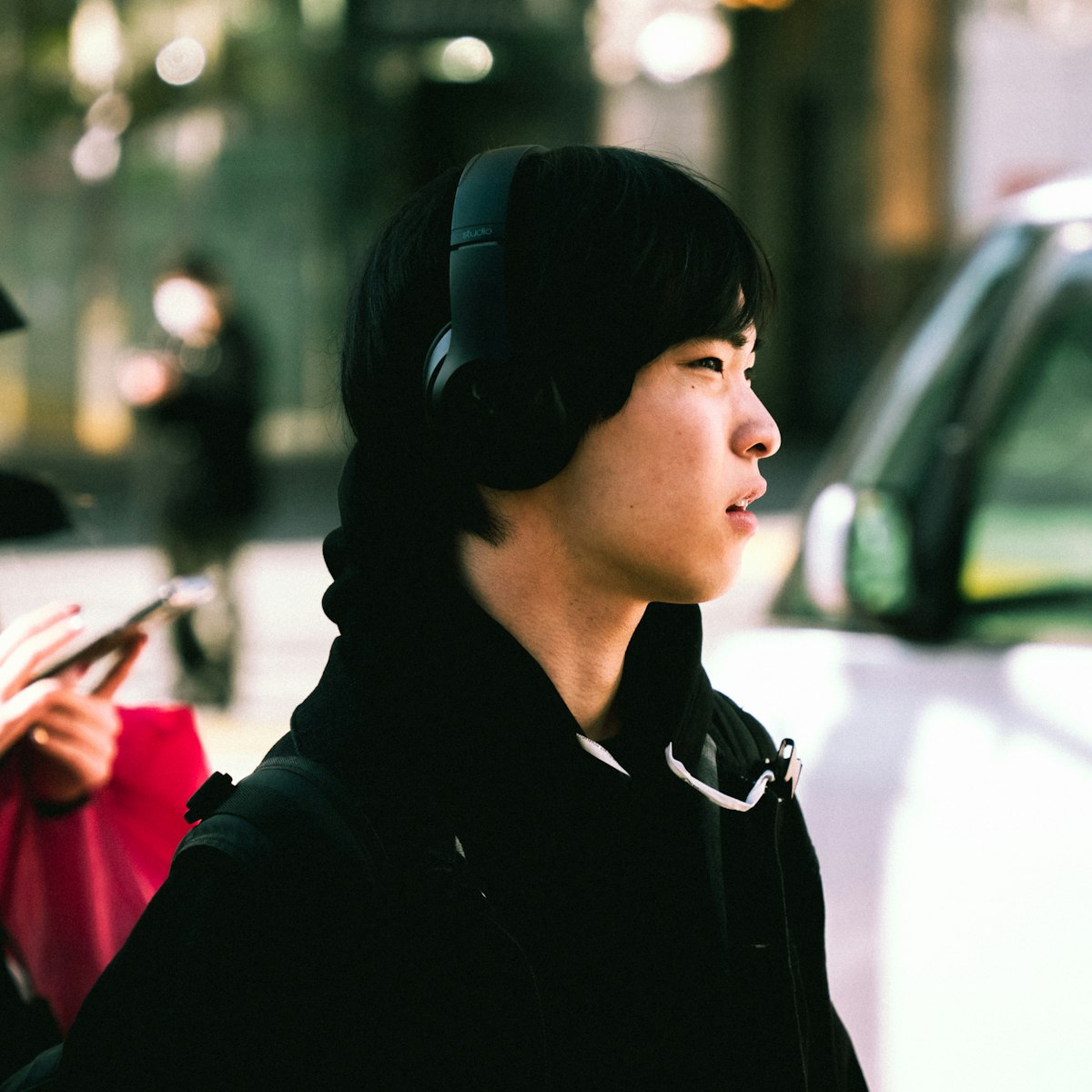 A young person wearing over-ear headphones while walking along a city street