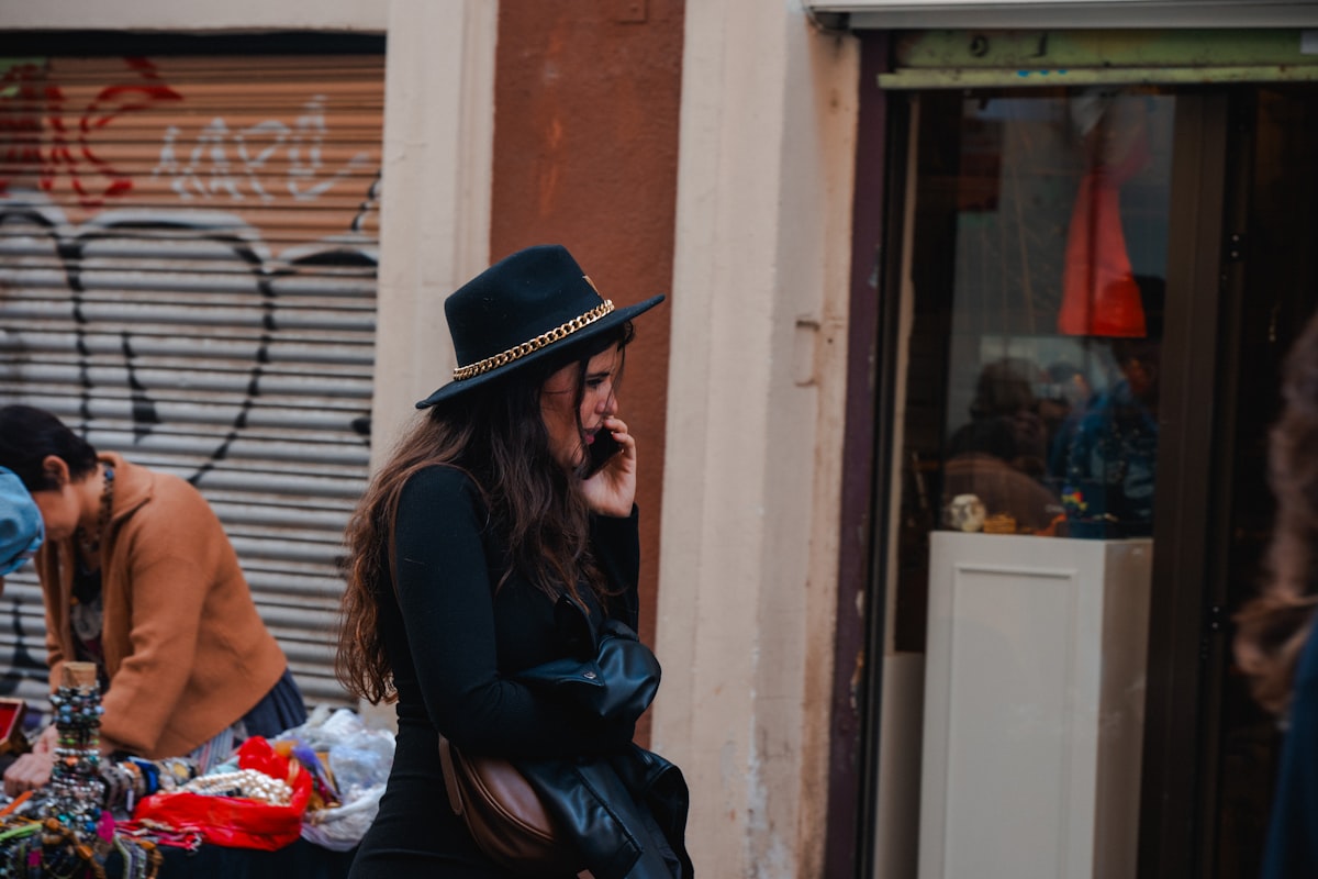 A woman in a hat talking on her phone on a city street